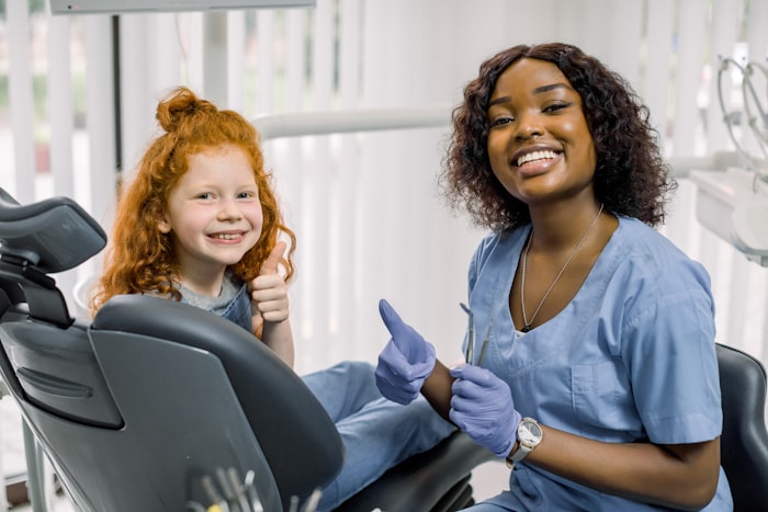 Dentista sorridente atendendo uma criança com carinho no consultório